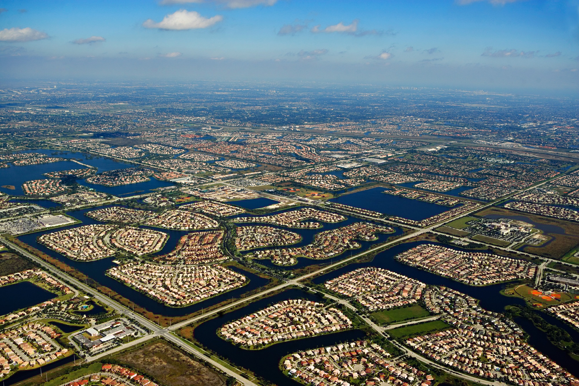 Aerial view of a residential area with numerous houses surrounded by water bodies, illustrating the concept of Flood Zone Insurance Rates.