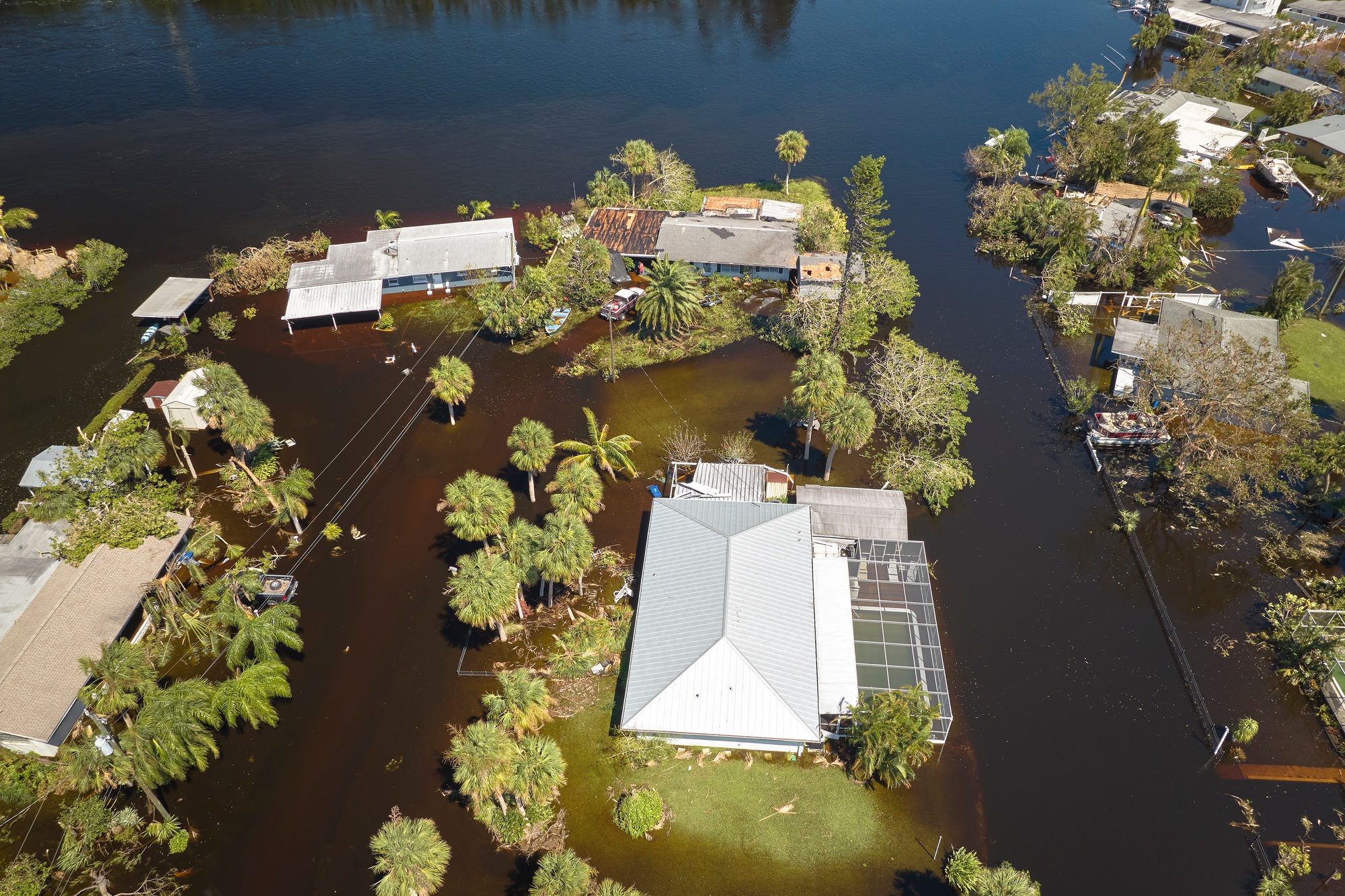 Aerial view of a flooded residential area in Florida, highlighting the need for Florida Flood Insurance with homes partially submerged in water surrounded by palm trees.